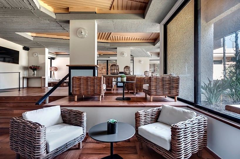 Spacious lounge area with woven rattan furniture, high ceilings, and large windows.