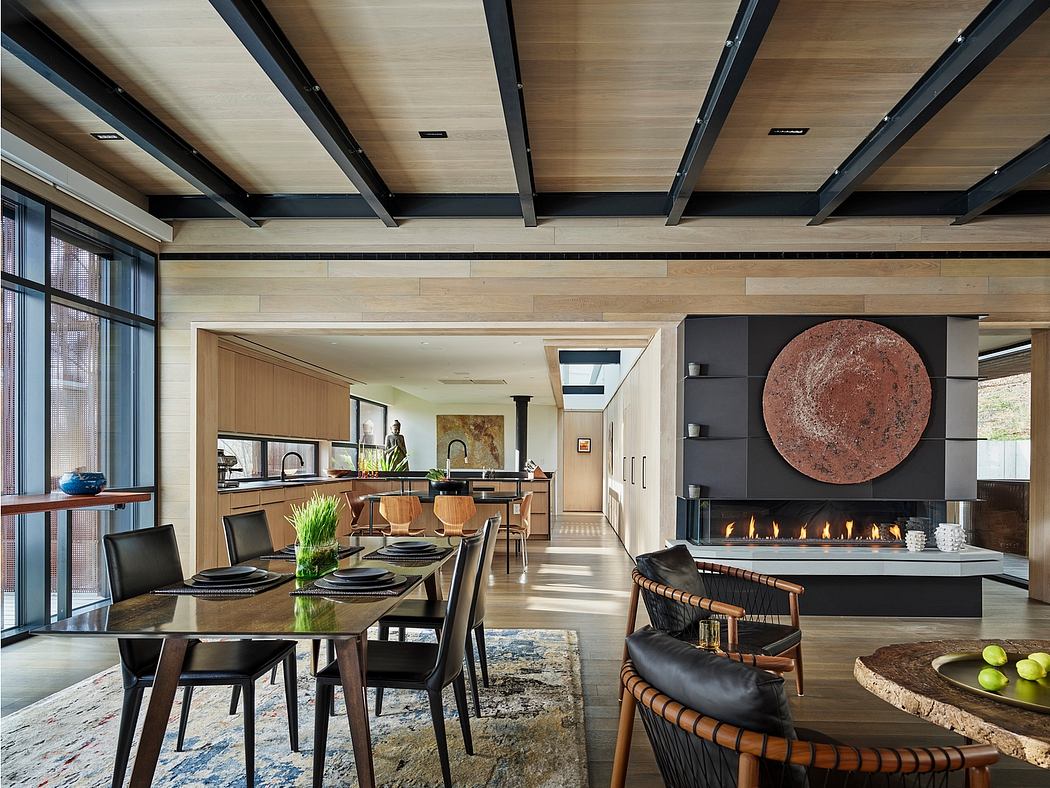 A modern, open-plan living space with wood beams, a gas fireplace, and an integrated kitchen.