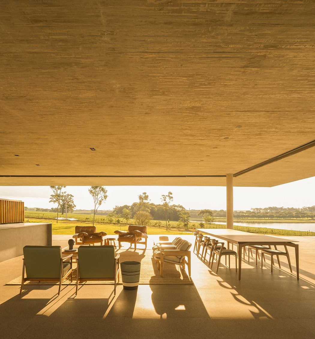 Cozy outdoor patio with wooden ceiling, comfy chairs, and scenic countryside view.