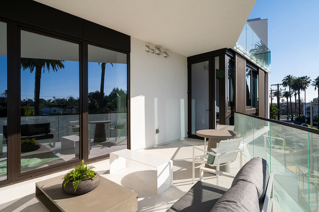 Modern, open-plan living space with glass walls, outdoor seating, and lush landscaping.