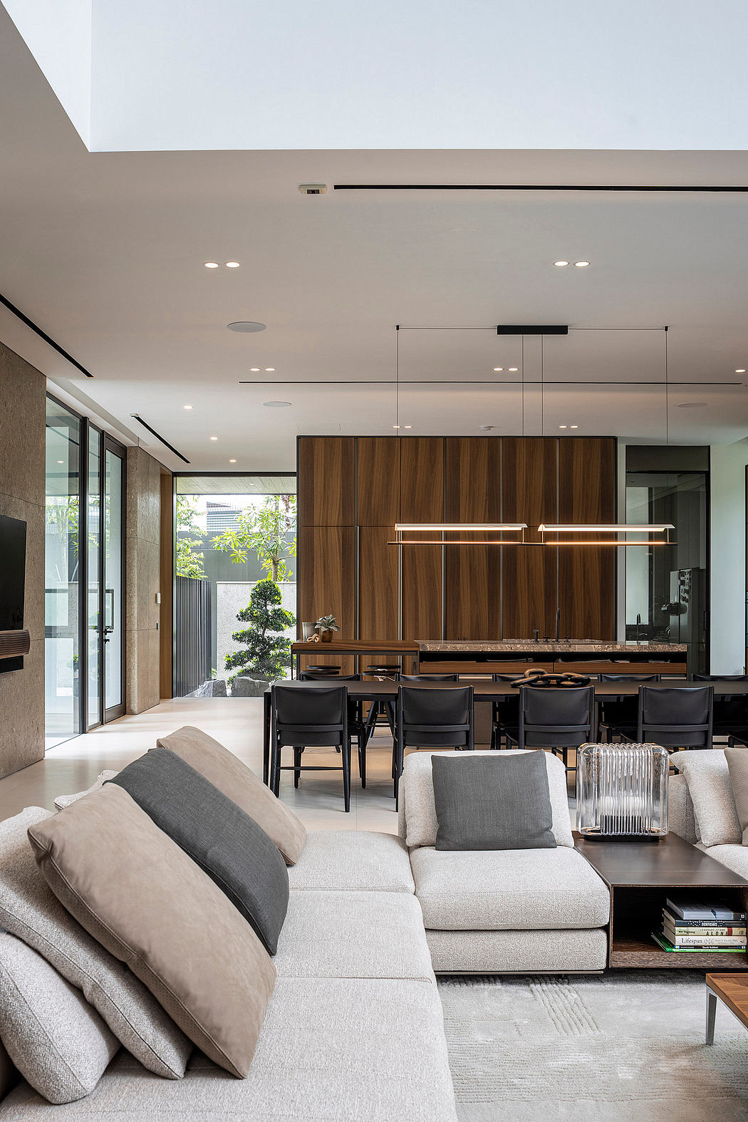 Elegant open-plan living space with sleek wooden cabinetry and modern light fixtures.