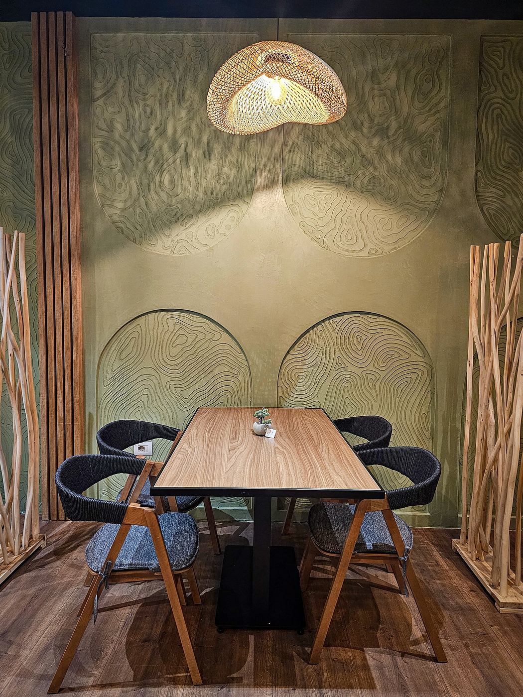 A cozy dining nook features a large woven lamp, textured wood paneling, and sleek chairs.
