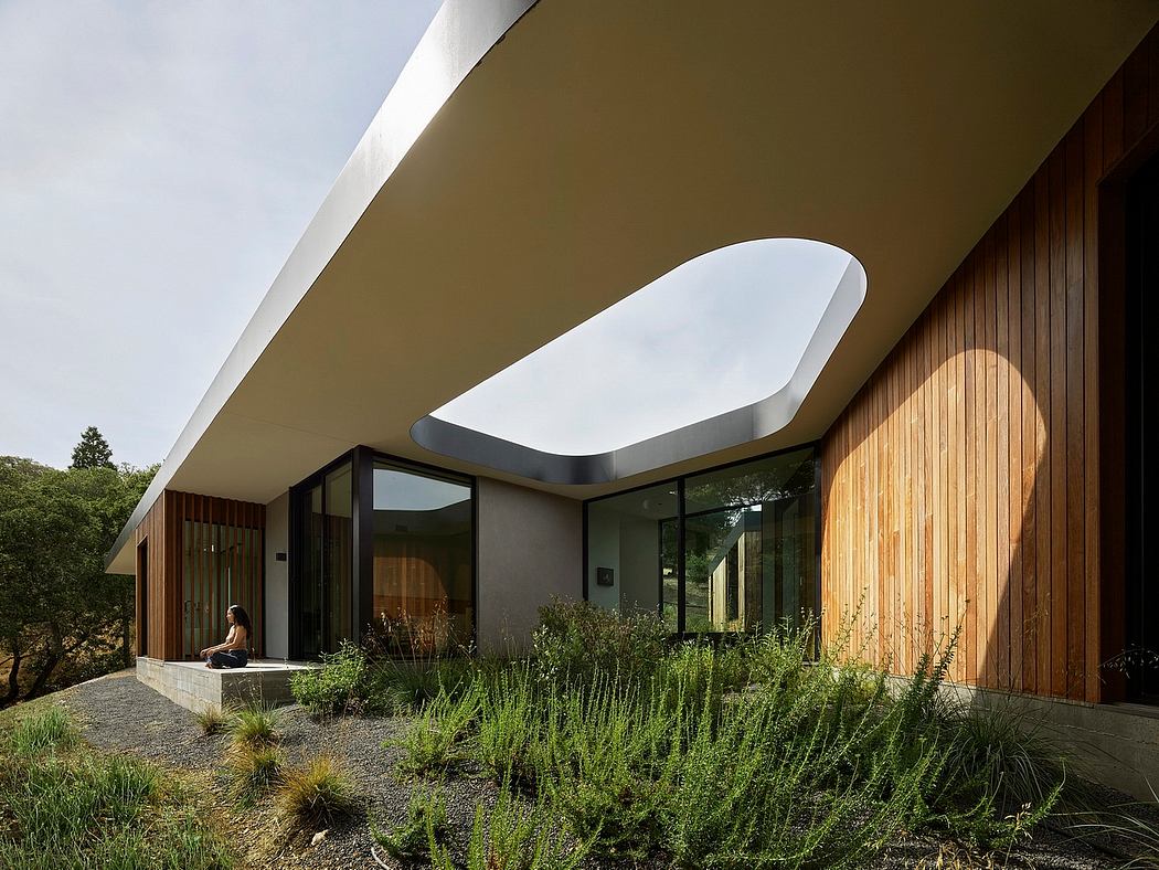 Striking architectural design featuring curved roof, glass walls, and lush landscaping.