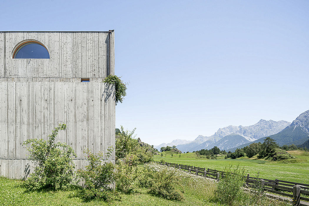 A modern, rustic-style building with arched windows set against a mountainous backdrop.