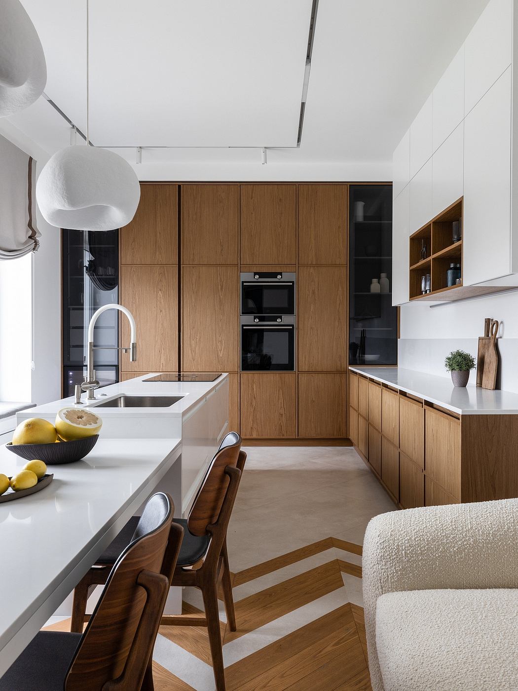 A modern kitchen with sleek oak cabinetry, white counters, and built-in appliances.