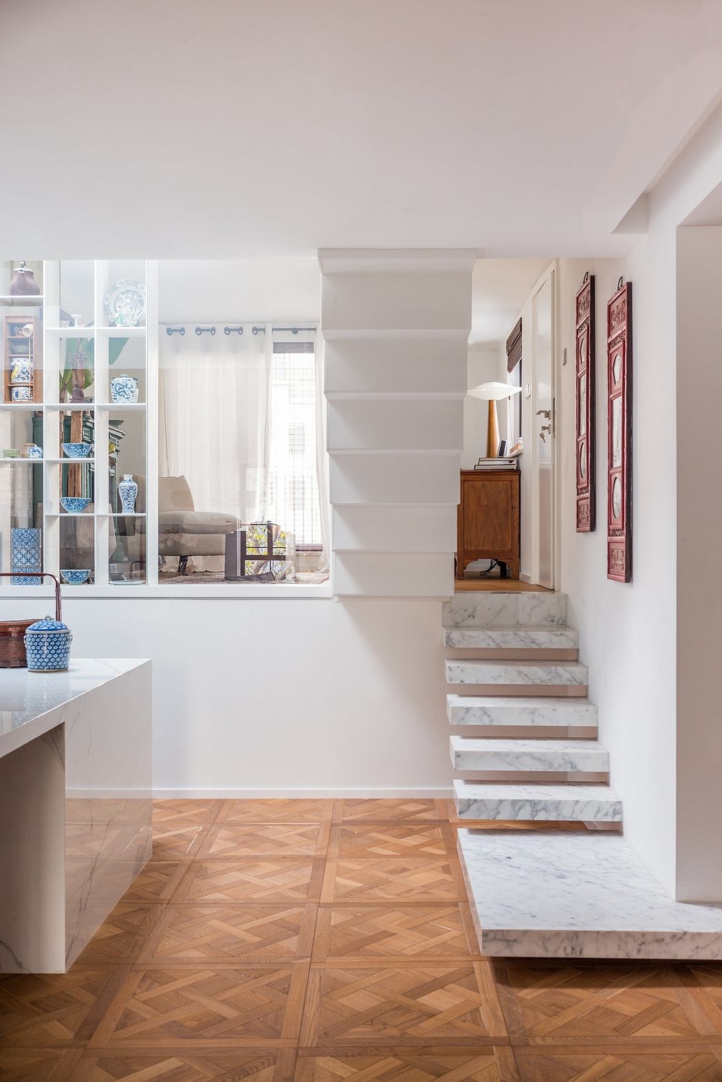 Elegant, minimalist interior with white walls, wooden floors, and a modern marble staircase.