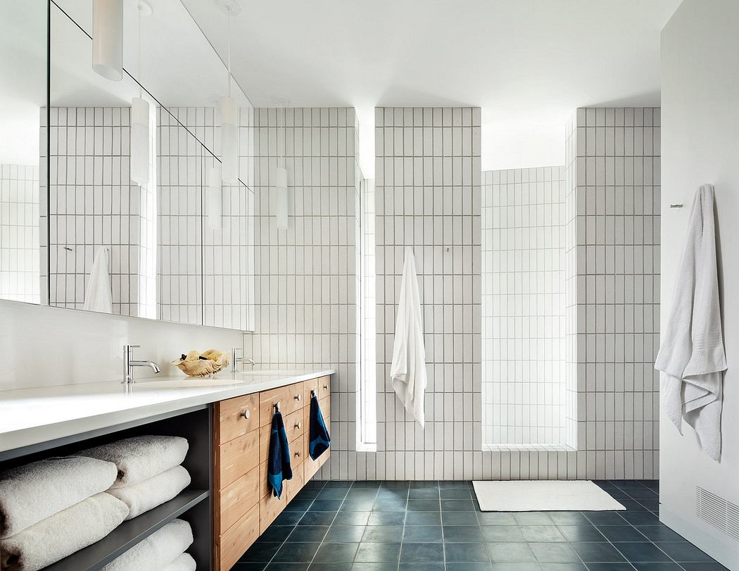 A modern, minimalist bathroom with geometric tiled walls, wooden vanity, and ample storage.