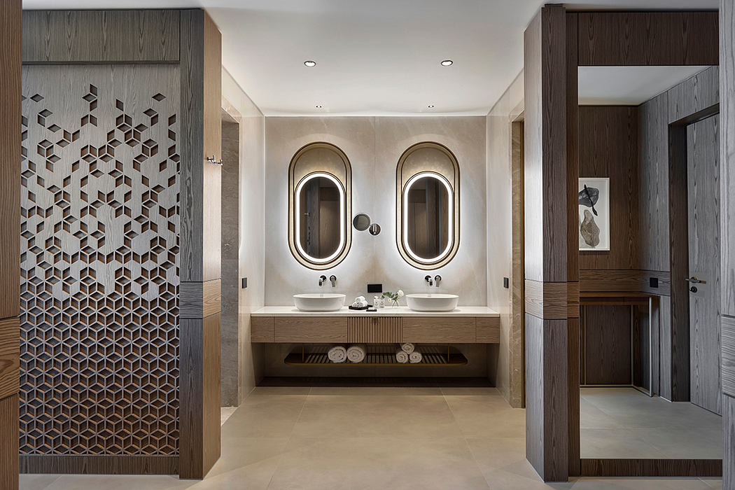 A modern bathroom with intricate tiled walls, dual vanity sinks, and a sleek, minimalist design.