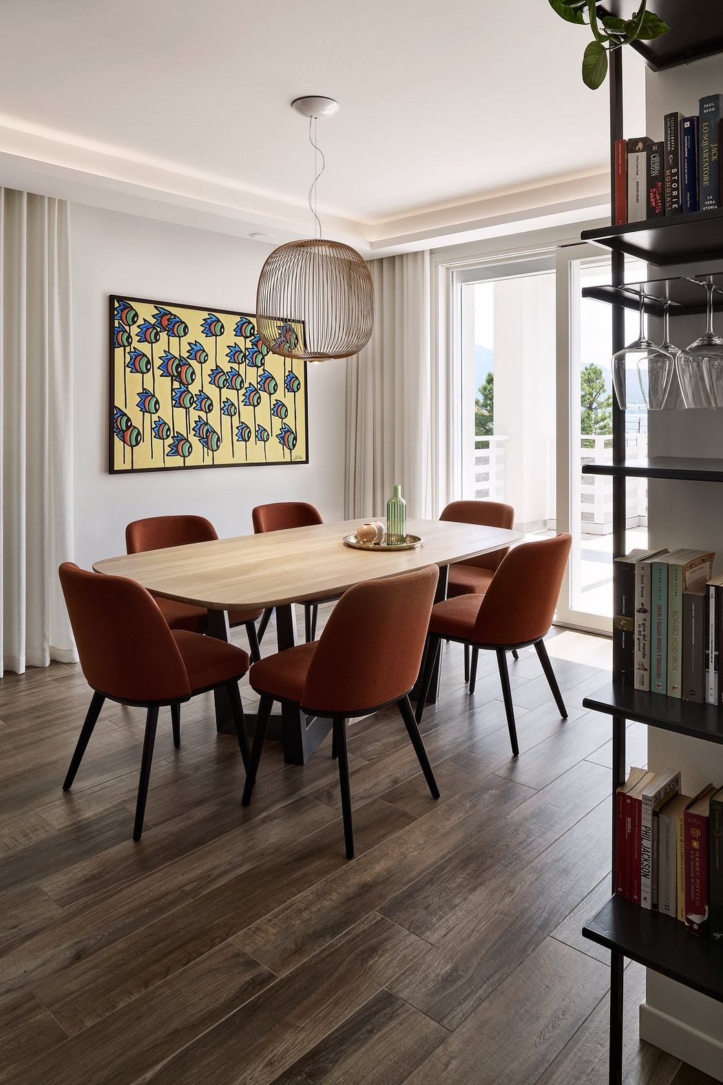 Cozy dining room with wood table, leather chairs, vibrant artwork, and pendant lighting.