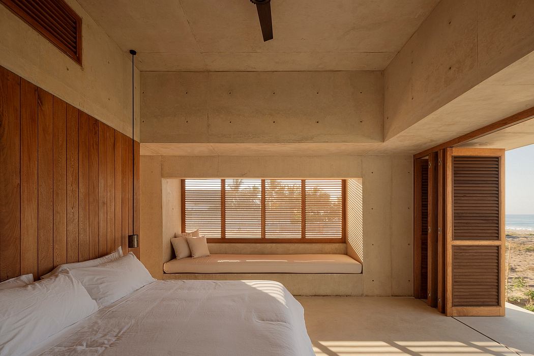 Serene beachfront room with floor-to-ceiling windows, concrete walls, and wooden accents.