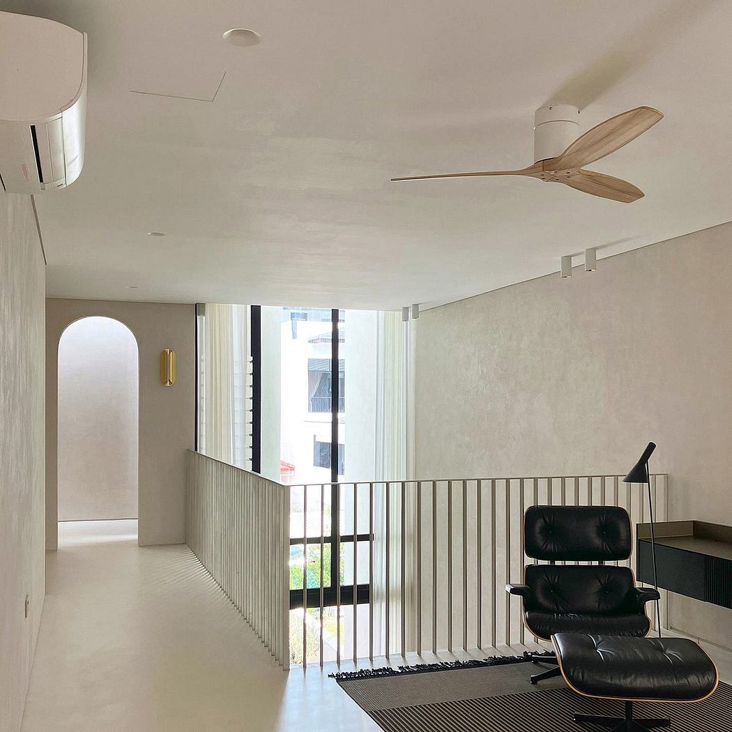 Modern minimalist apartment with sleek ceiling fan, arched window, and leather chair.