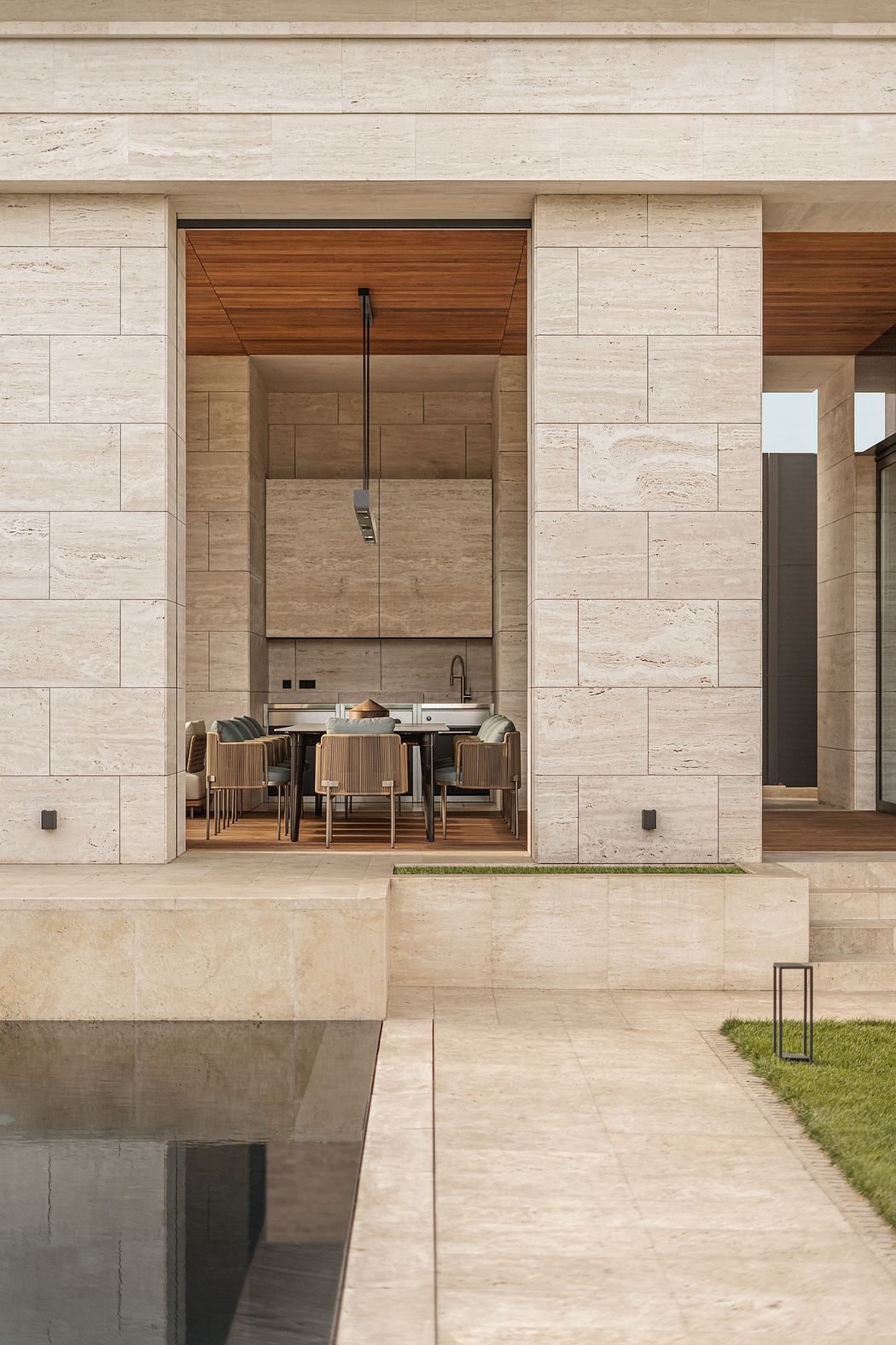 A modernist facade of travertine and wood frames an inviting interior dining area.