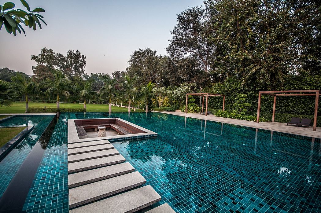 Tranquil outdoor pool surrounded by lush greenery, with a tiled platform and cozy alcove.