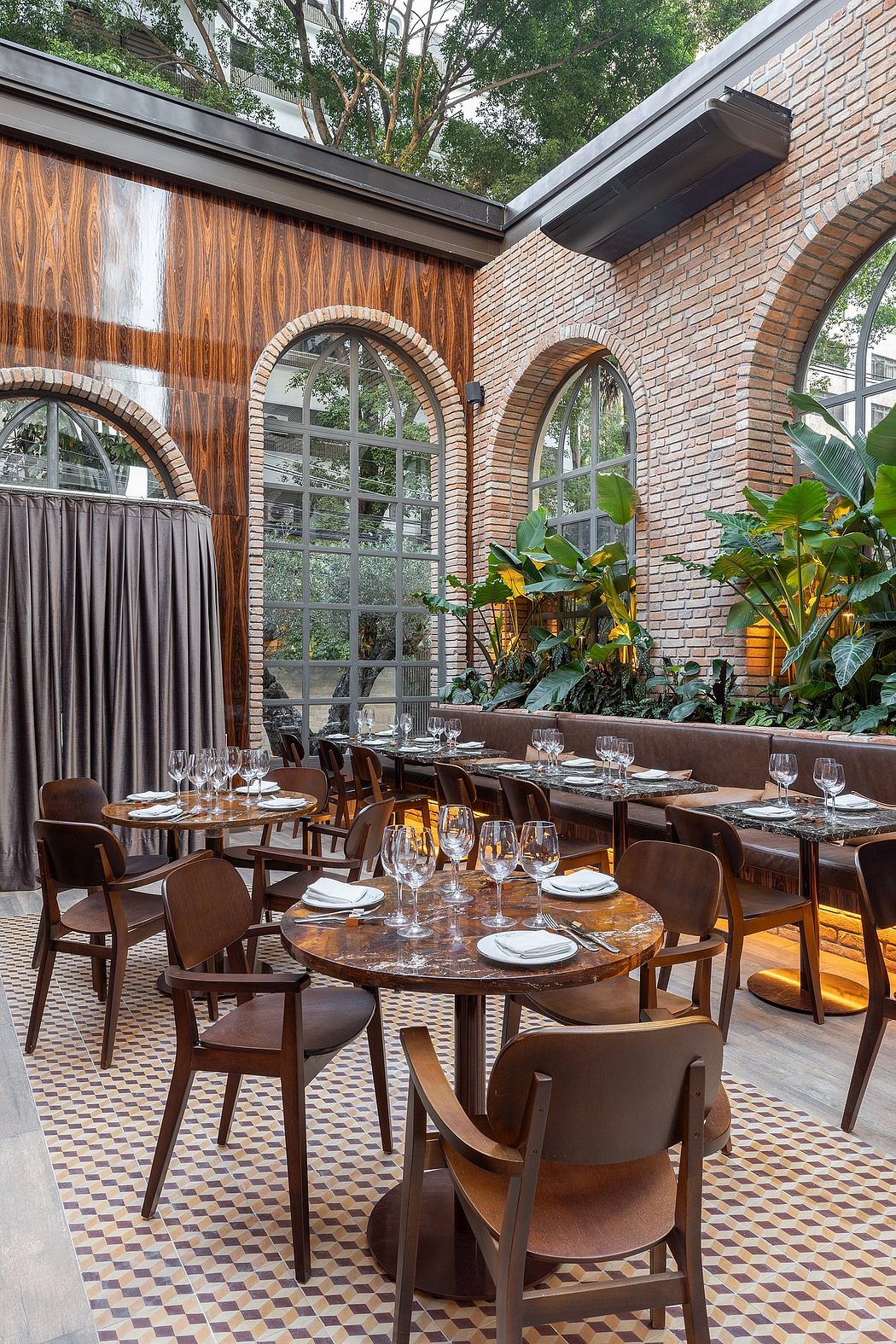 Cozy restaurant setting with brick arched windows, wooden accents, and lush greenery.