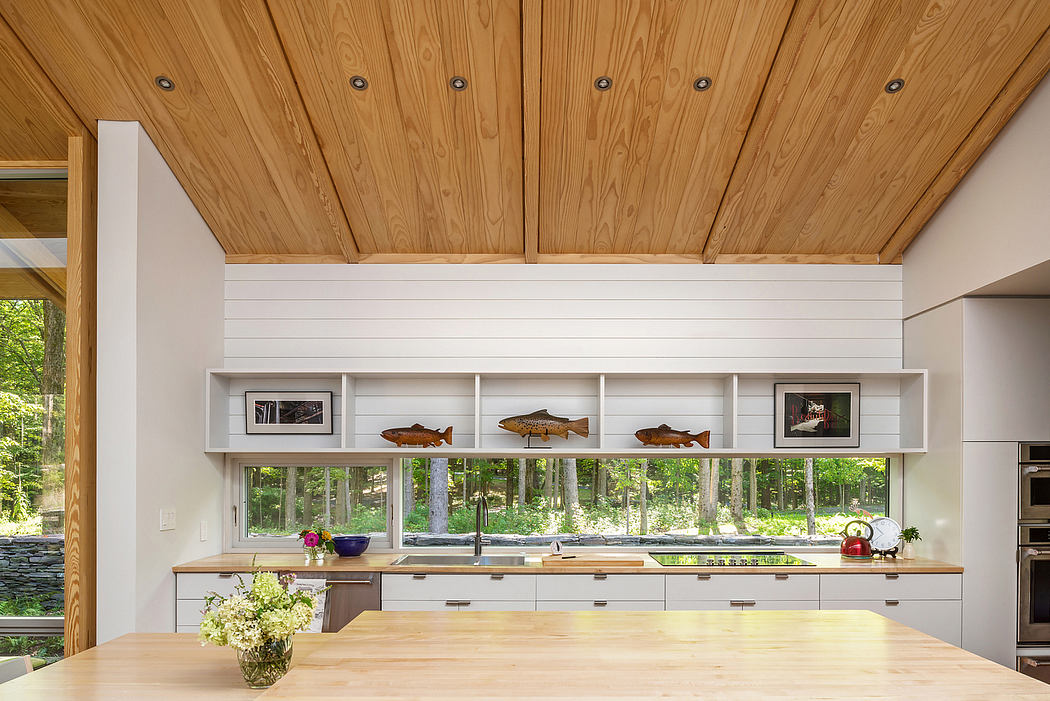 A modern kitchen with a wooden ceiling, white cabinetry, and decorative fish sculptures.