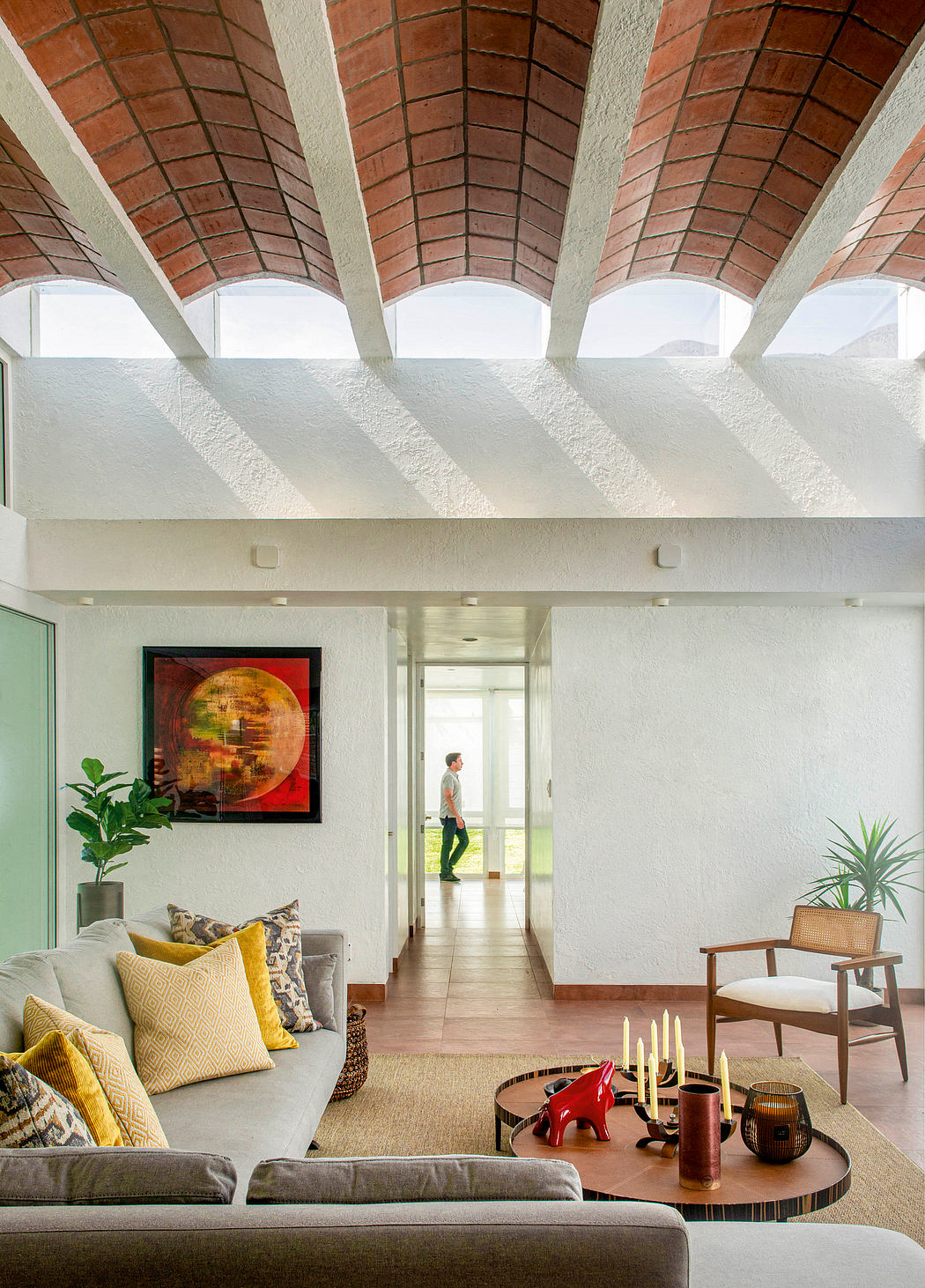 A spacious living room with a vaulted brick ceiling, modern furniture, and artwork.