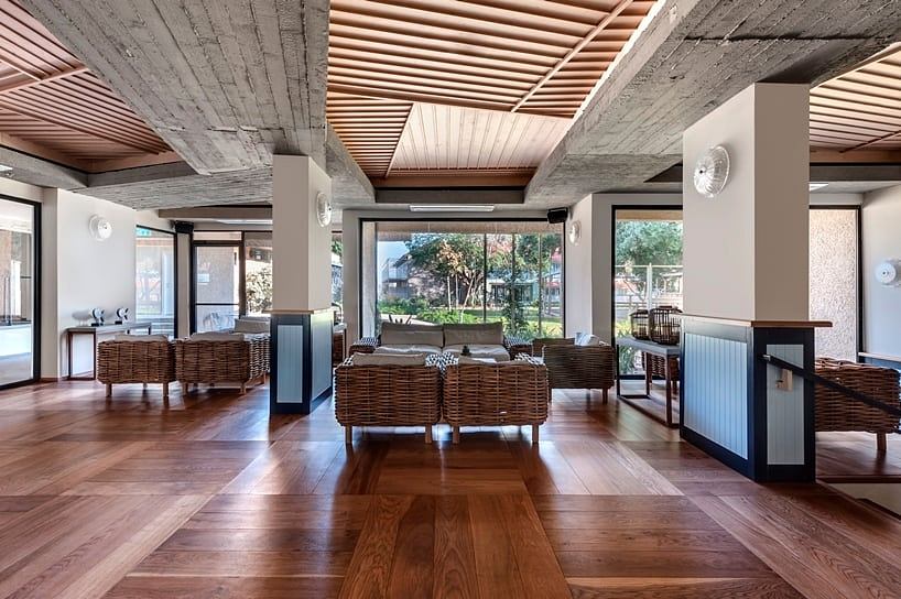 Warm wooden ceiling beams contrast with gray concrete walls, creating a modern lounge space.
