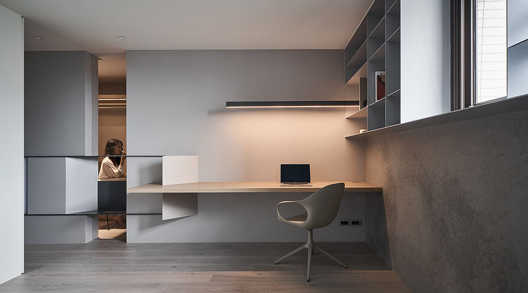 Minimalist office space with sleek built-in desk, storage units, and modern swivel chair.