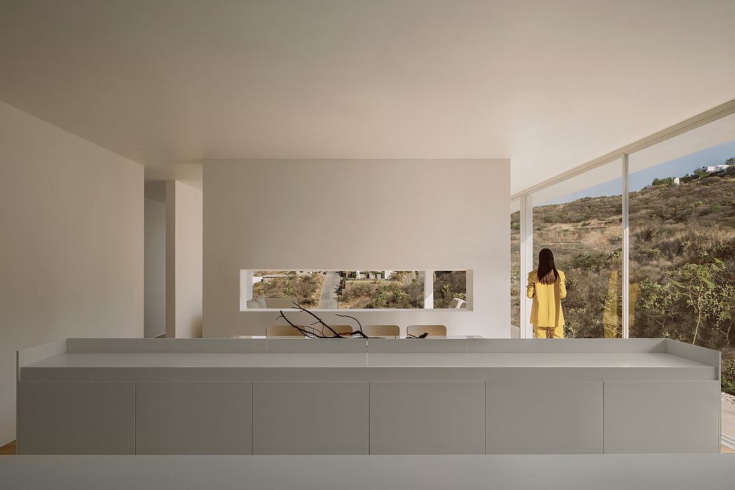 Minimalist modern interior with large windows overlooking a natural landscape.