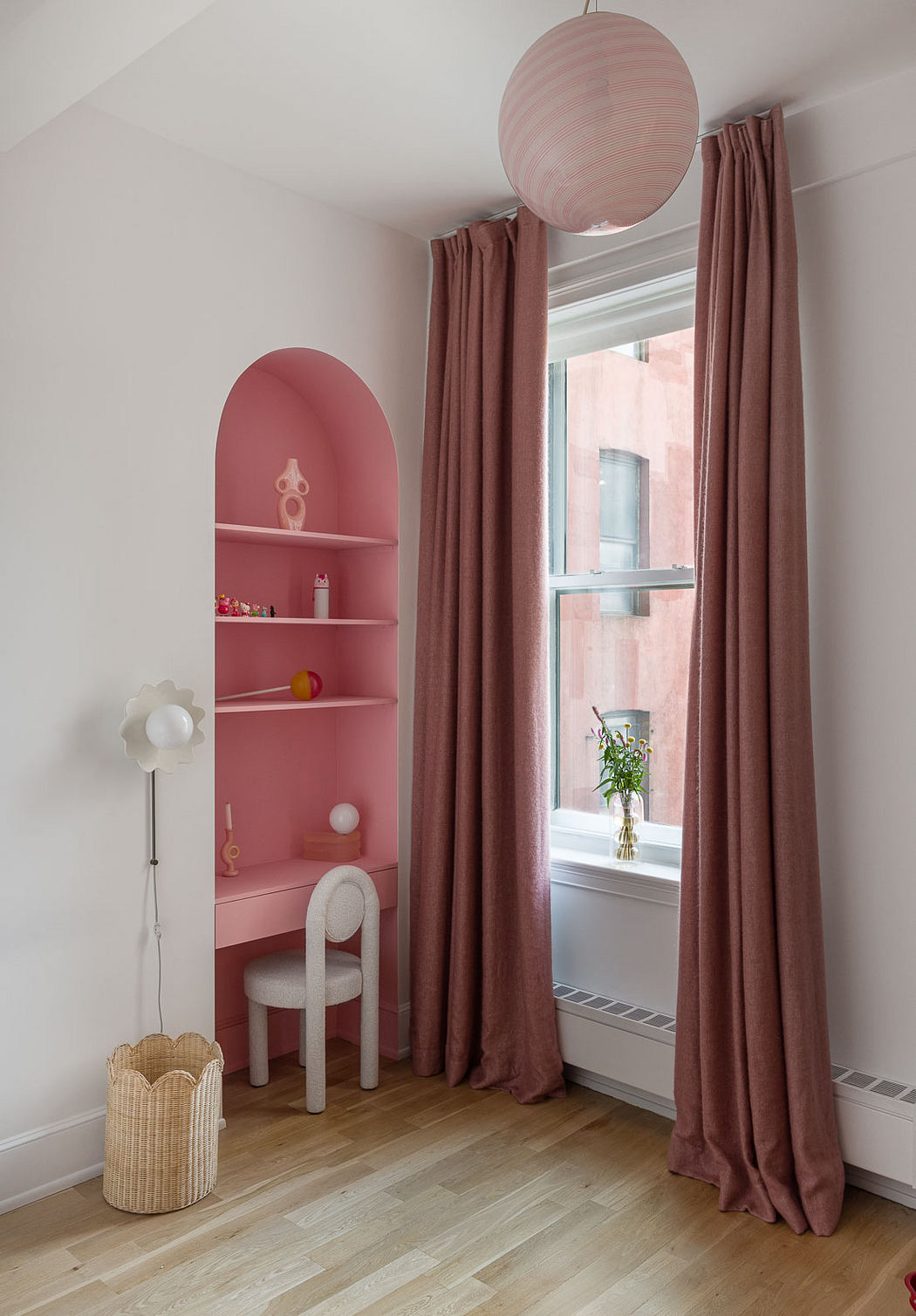 A cozy, pink-accented room with a striking arched shelf, curtains, and a woven basket.