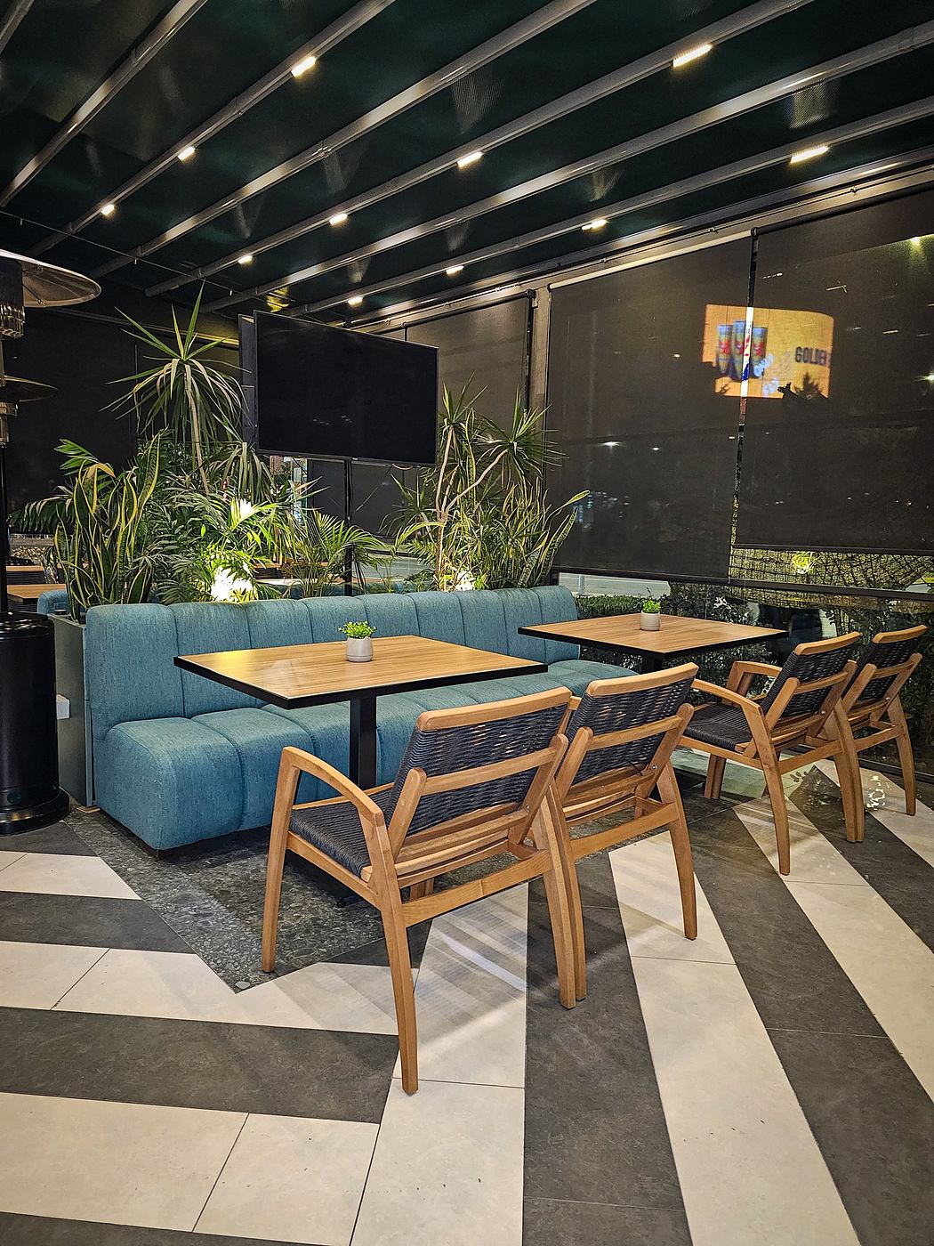 Cozy lounge area with plush teal sofa, wood furniture, and lush greenery accents.