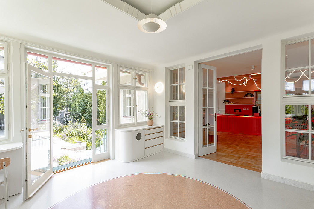 Bright, inviting living space with large windows, built-in cabinetry, and vibrant red accent wall.