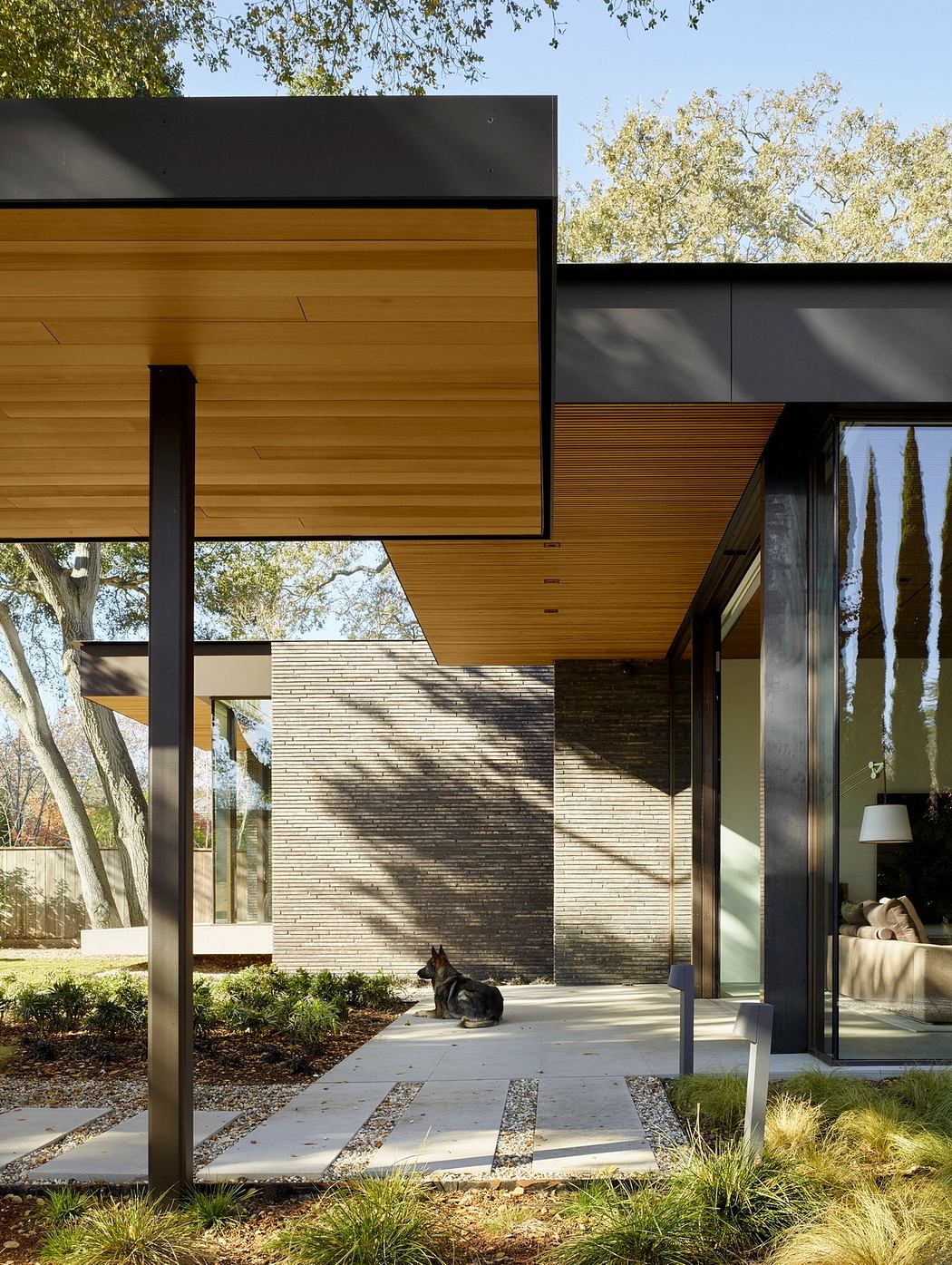 Modern wood and stone exterior with recessed entryway and landscaping details.