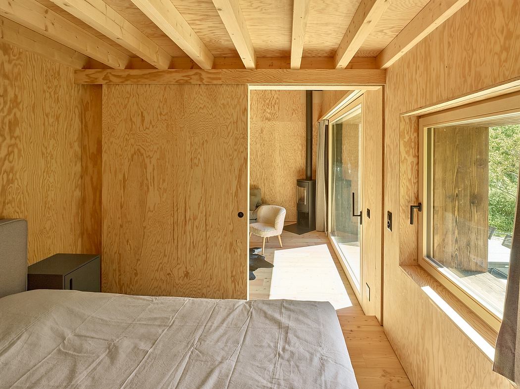 Cozy wooden cabin interior with exposed ceiling beams, sliding glass doors, and minimal furnishings.