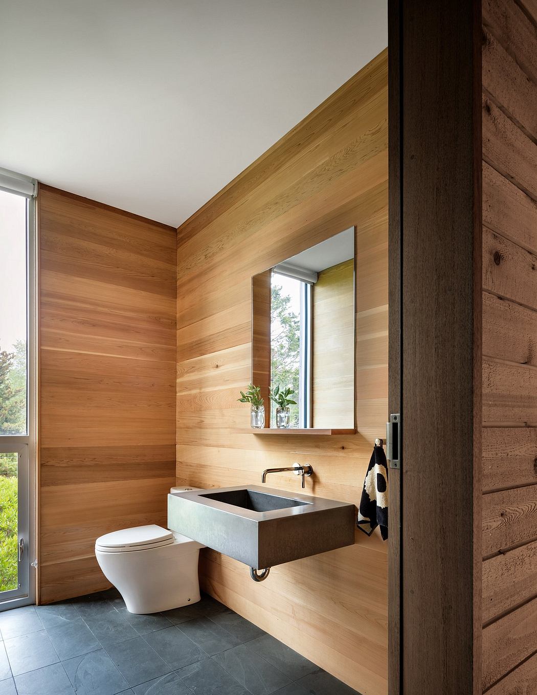 Rustic bathroom with wooden walls, rectangular sink, and wall-mounted mirror.