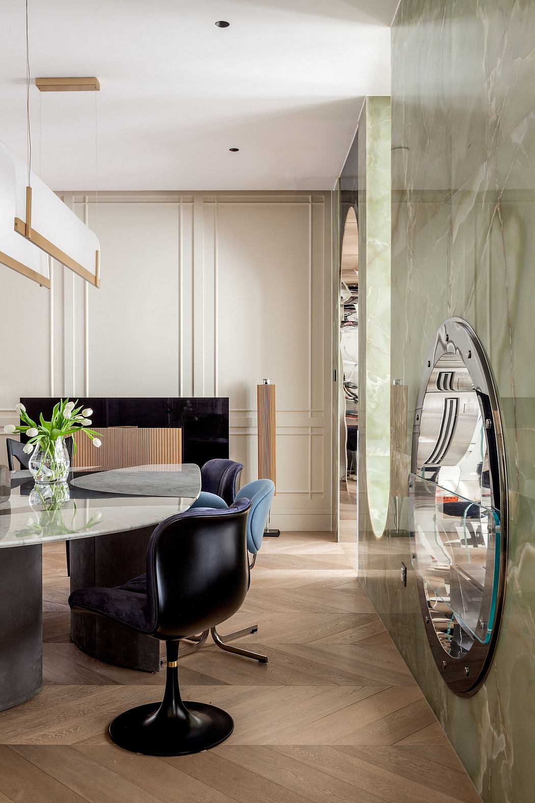 A modern, elegantly designed dining area with a marble-topped table, plush seating, and a large mirror.