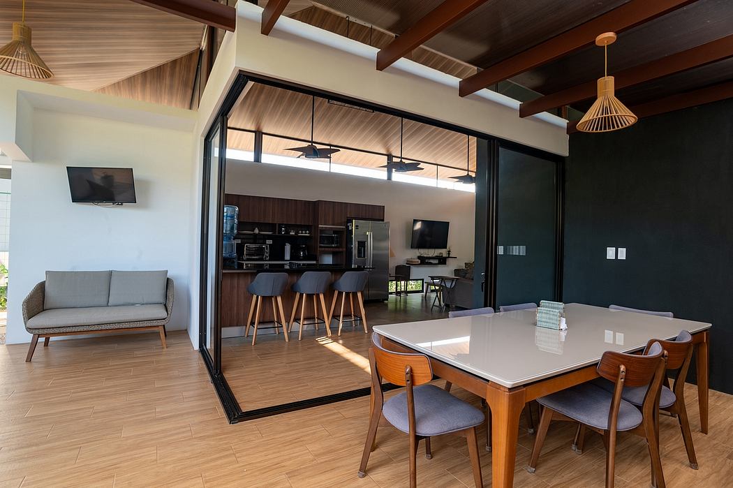 Spacious open-concept living area with wooden beams, modern furniture, and kitchen.