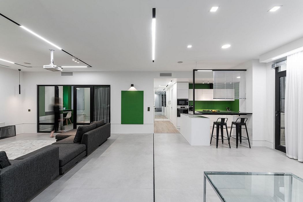 Spacious, modern open-plan apartment with minimalist decor, green accents, and sleek kitchen.