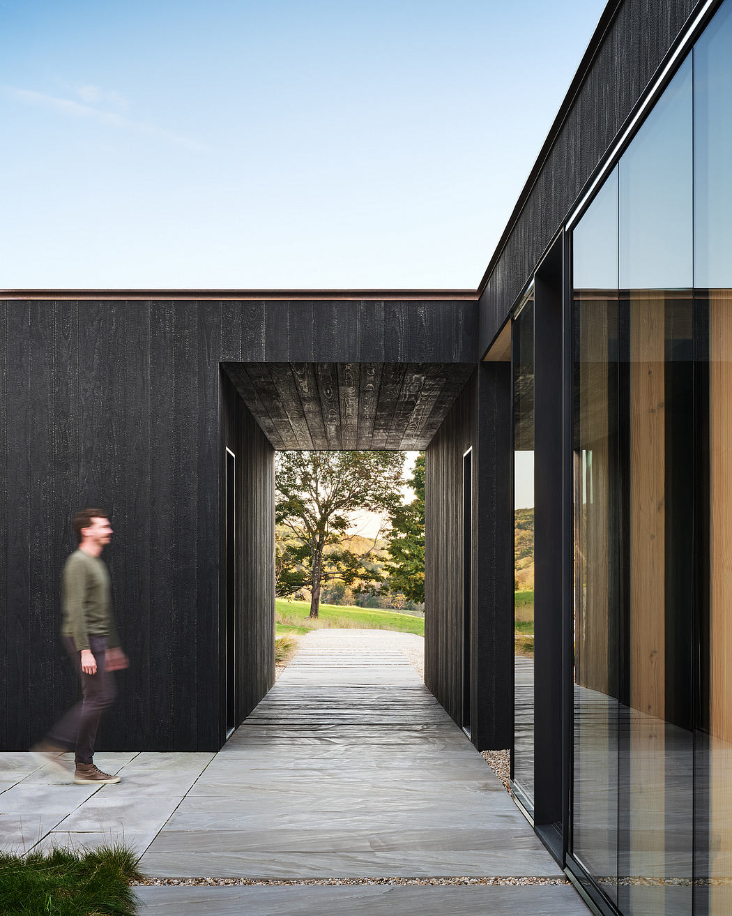 Sleek, modern architecture with black wood and glass panels framing a scenic nature view.