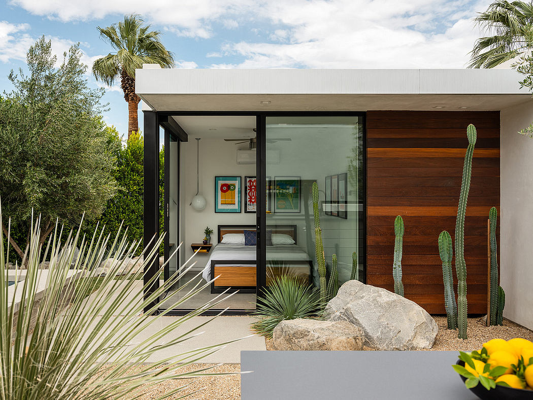 Modern minimalist home with large glass walls, wood paneling, and desert landscaping.