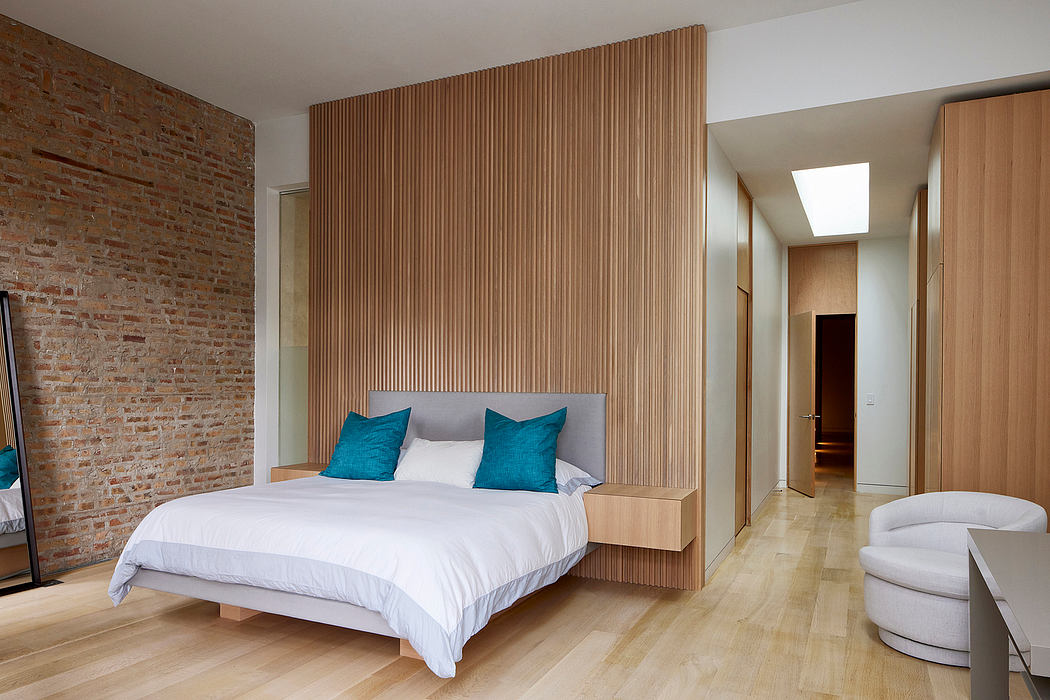 A modern bedroom with a wood-paneled accent wall, white bed, and turquoise accents.