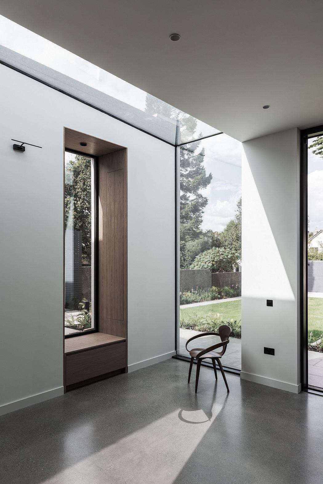 Minimalist interior with sleek glass panels, wooden accents, and views of lush greenery.