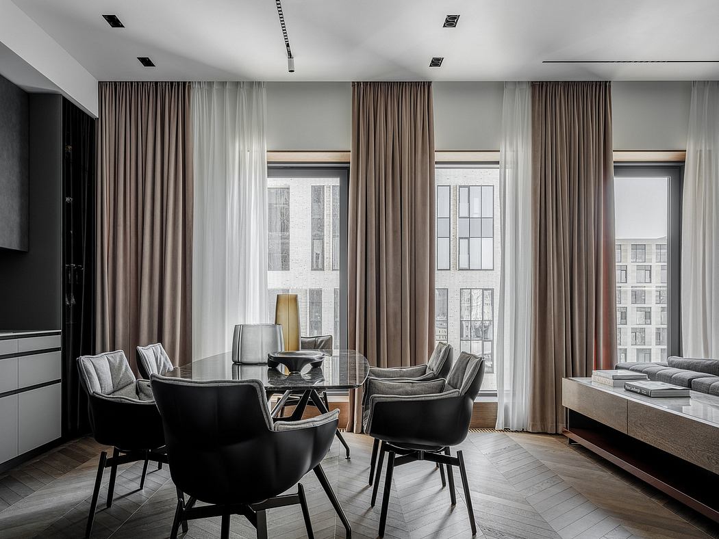 A modern, minimalist living room with large windows, dark furniture, and textured curtains.