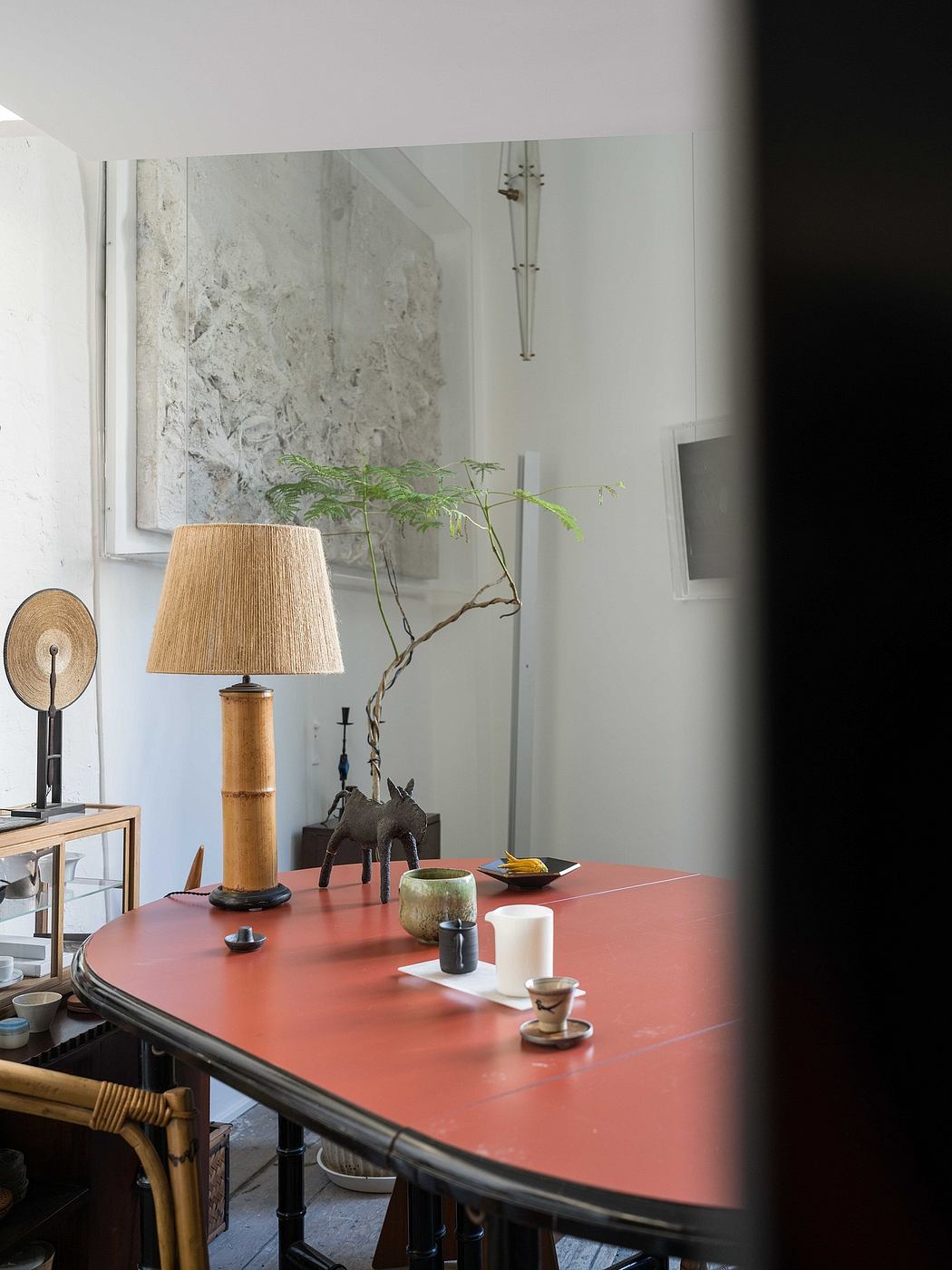 Cozy interior with a bold red dining table, rustic lighting, and minimalistic decor.