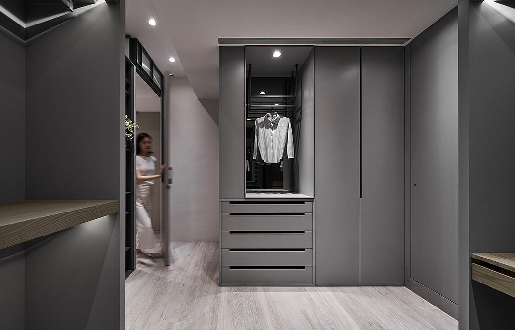 A sleek, modern closet with built-in drawers and hanging space against a dark gray backdrop.