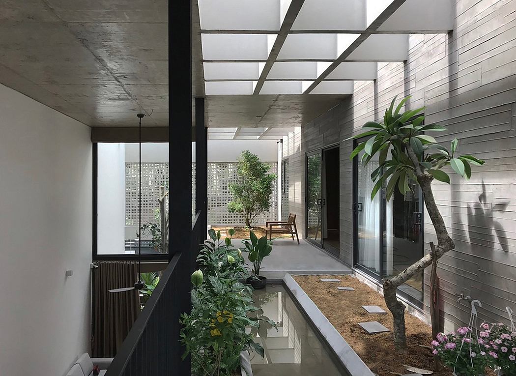 A contemporary indoor patio with concrete walls, skylights, and lush greenery.