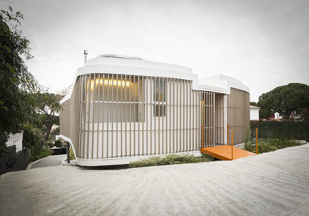 A modern, minimalist building with a distinctive white exterior and angled wooden slats.