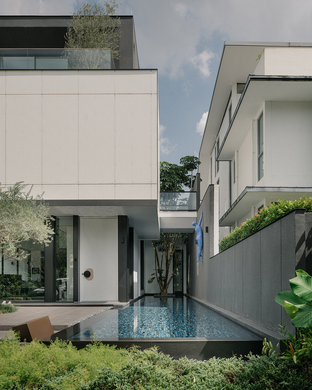 A modern, geometric building with a reflection pool and lush greenery surrounding it.