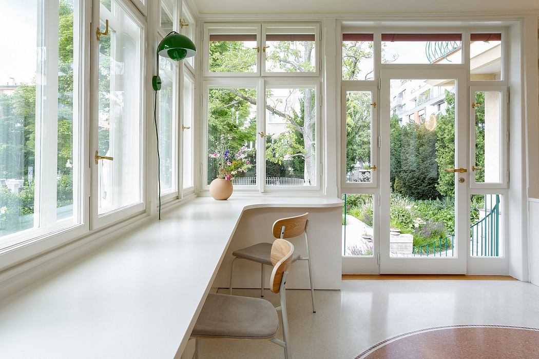 A bright, airy room with large windows overlooking a lush, green outdoor space.