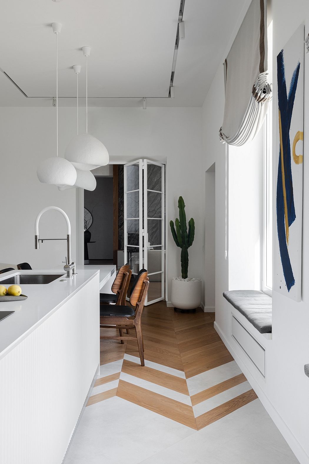 Modern kitchen with chevron hardwood floor, minimalist decor, and large windows.
