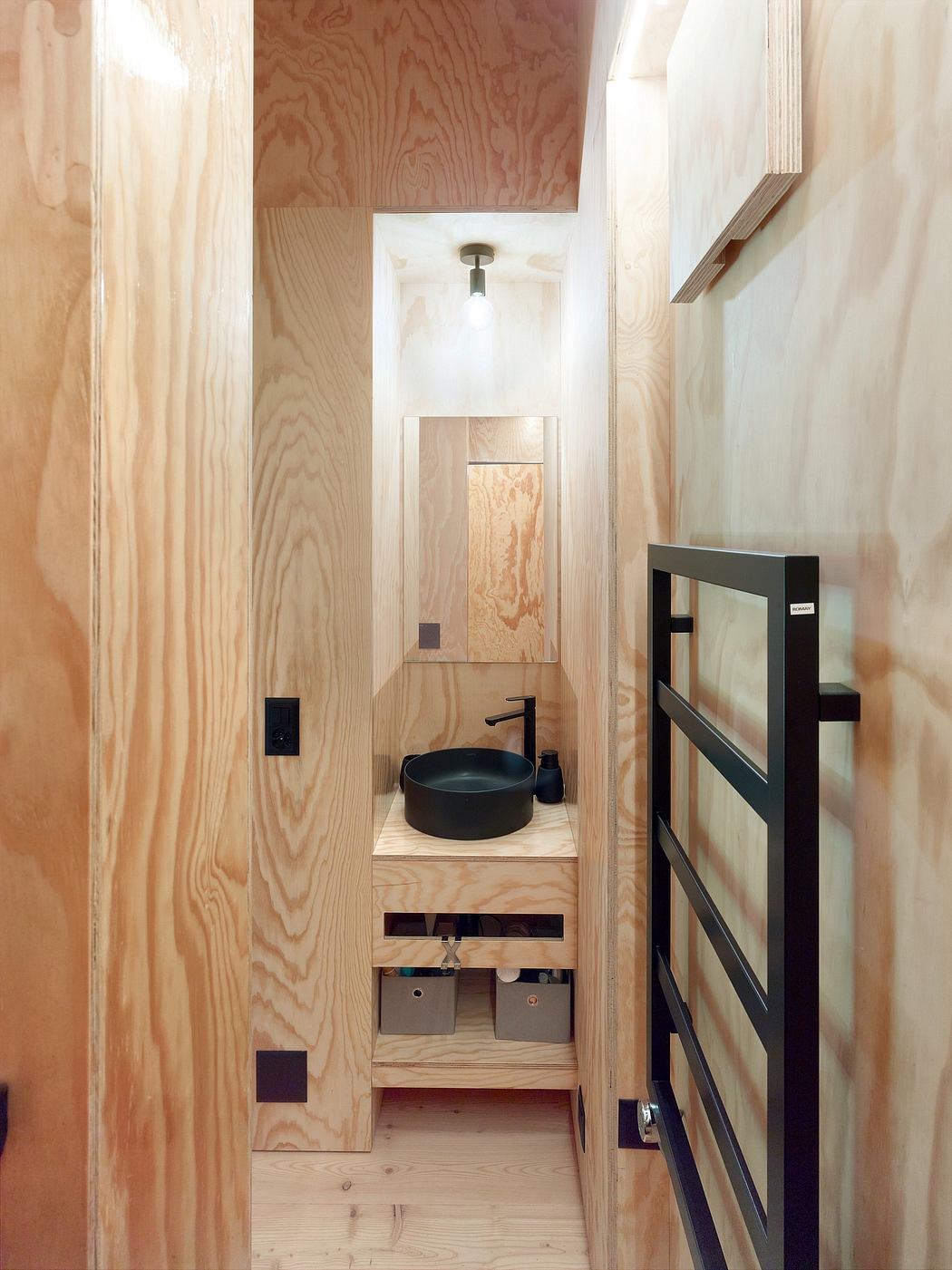 Compact bathroom design with minimalist wooden walls, floating vanity, and black accents.