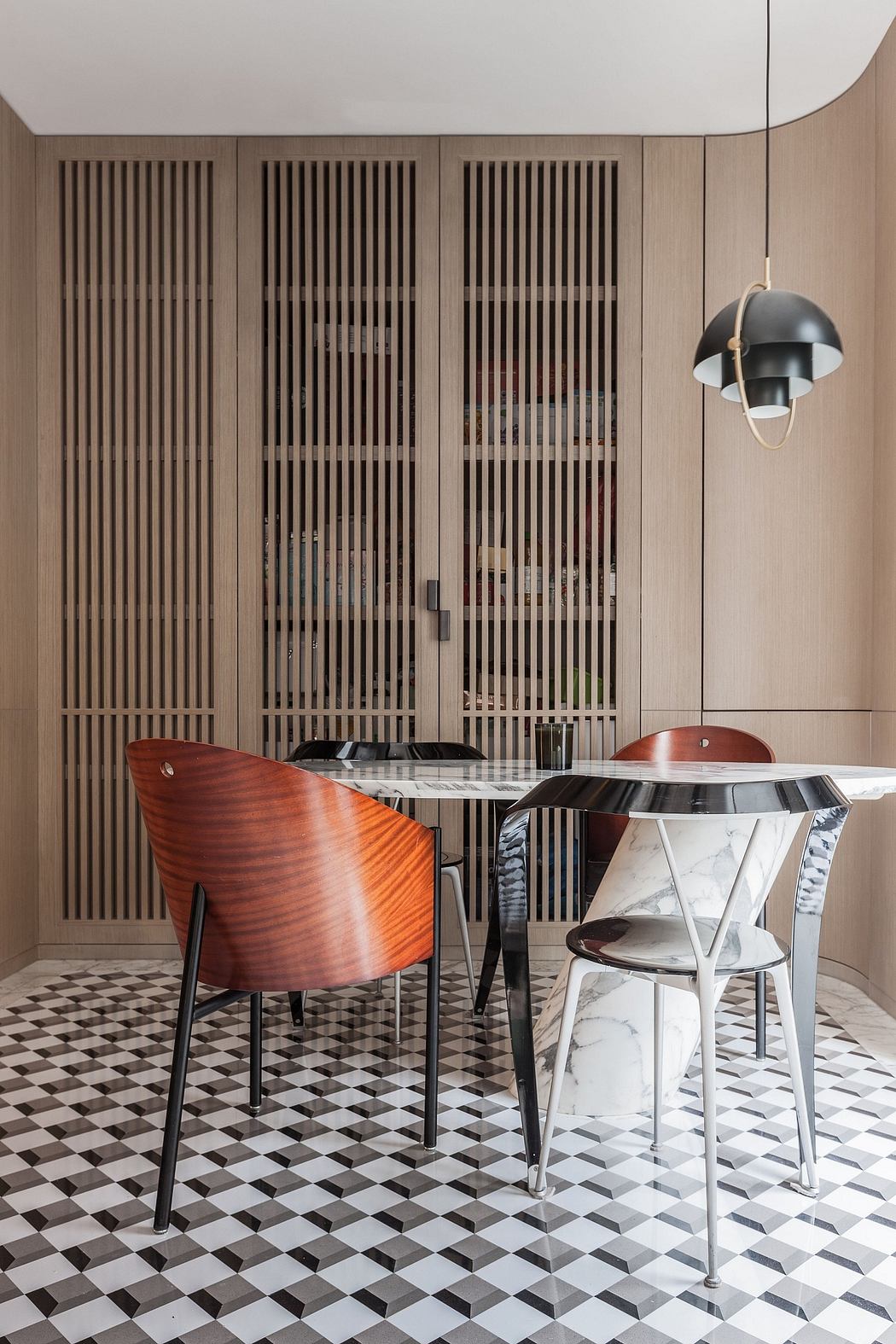 A modern dining room with slatted wood walls, a marble table, and a black pendant light.