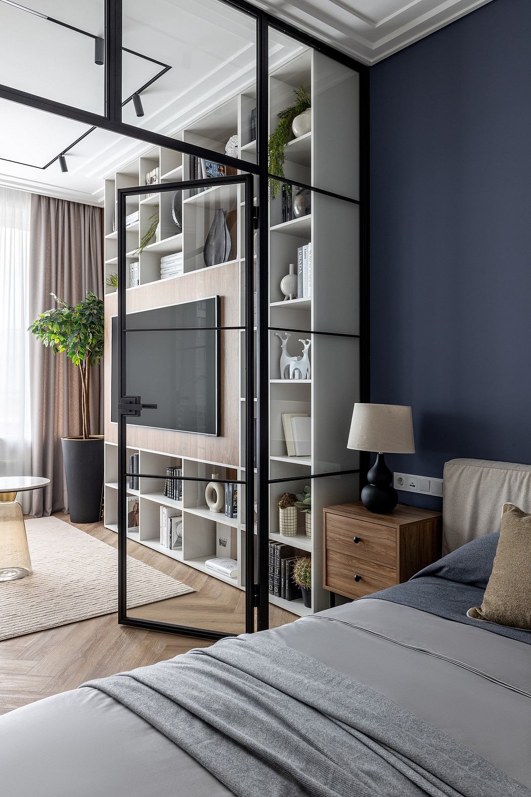 Sleek black-framed shelving unit divides the modern bedroom, creating visual interest.