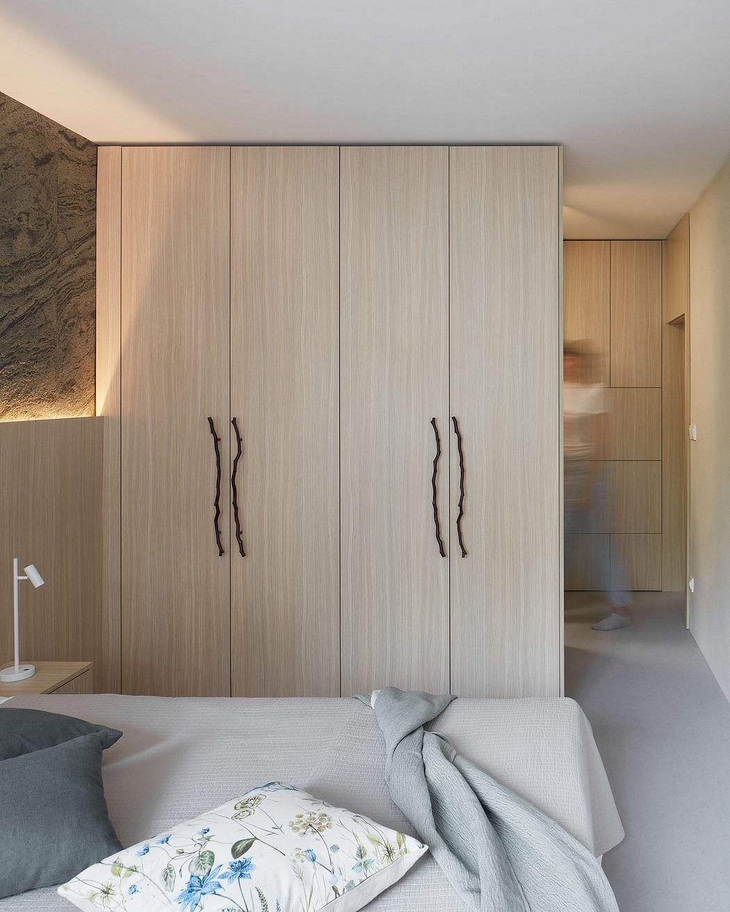 A minimalist bedroom with a large, built-in wooden wardrobe featuring sleek, modern handles.