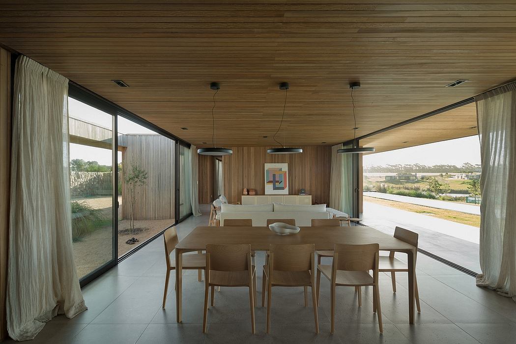 Spacious open-plan interior with wooden walls, large windows, and modern furniture.