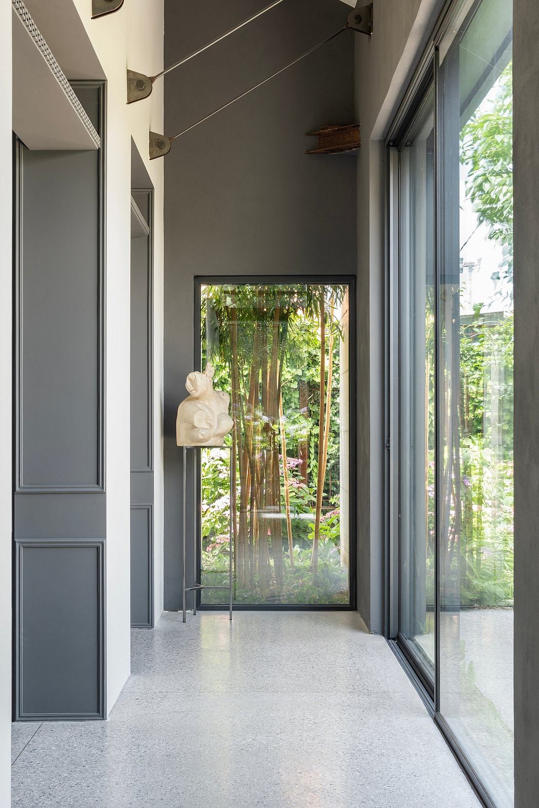 Sleek, modern interior with full-height glass doors, dark walls, and a sculptural element.